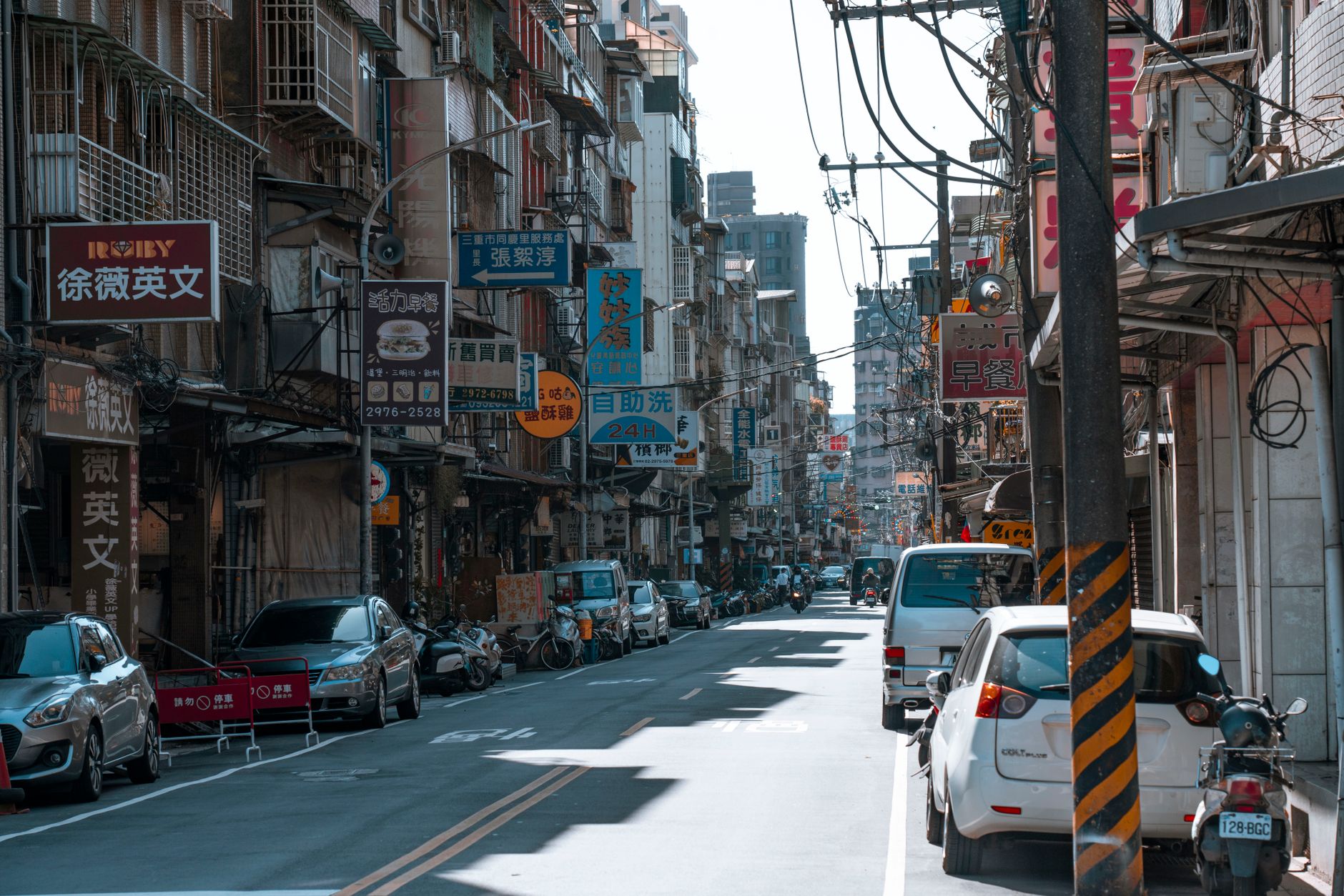 A busy street lined with cars and various colorful business signs on a sunny day. — MT4 for iOS vs Android: Which Mobile Plat