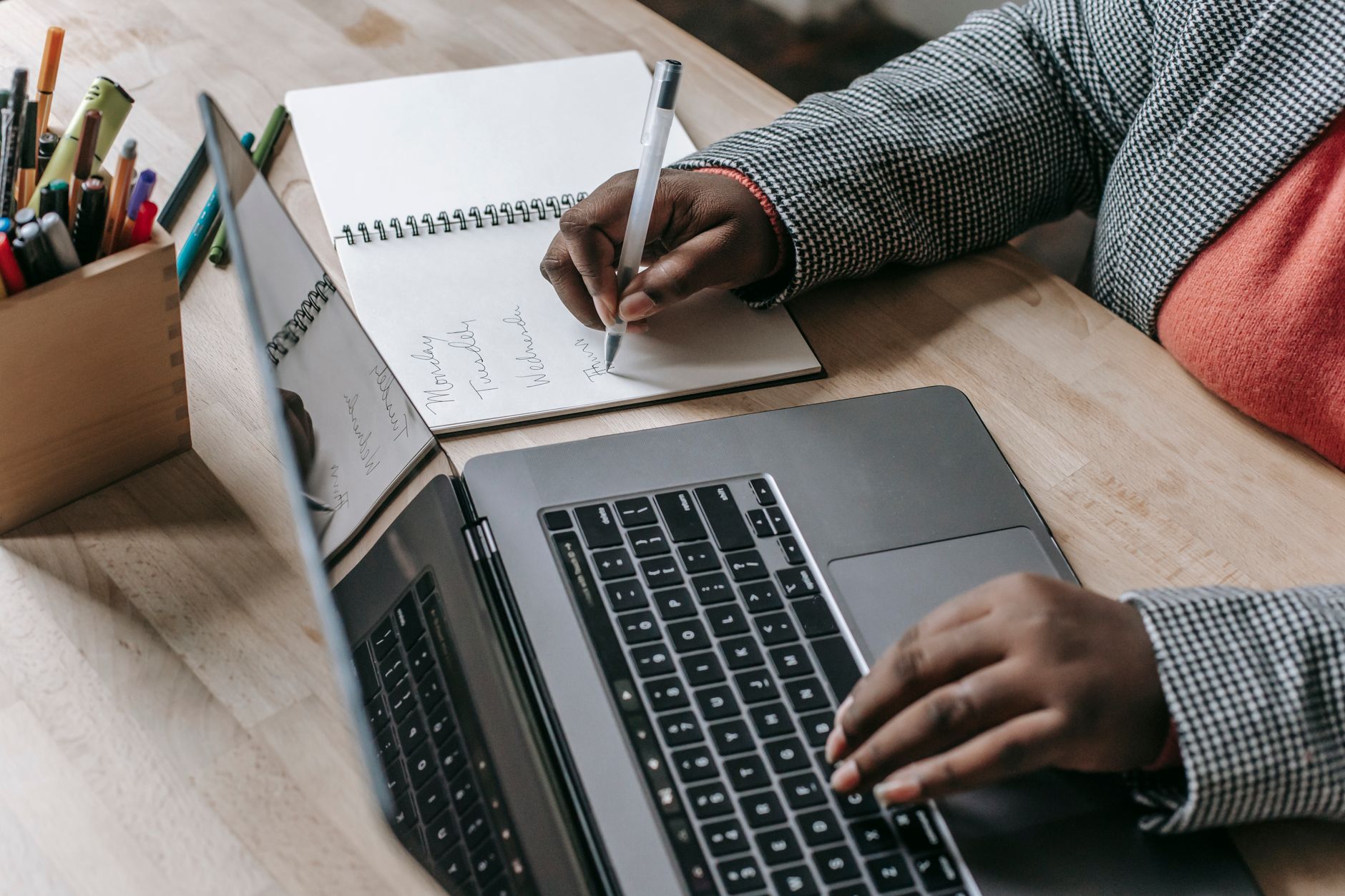 Crop unrecognizable African American female in formal wear writing notes in notepad while working on laptop — Multisolve: The