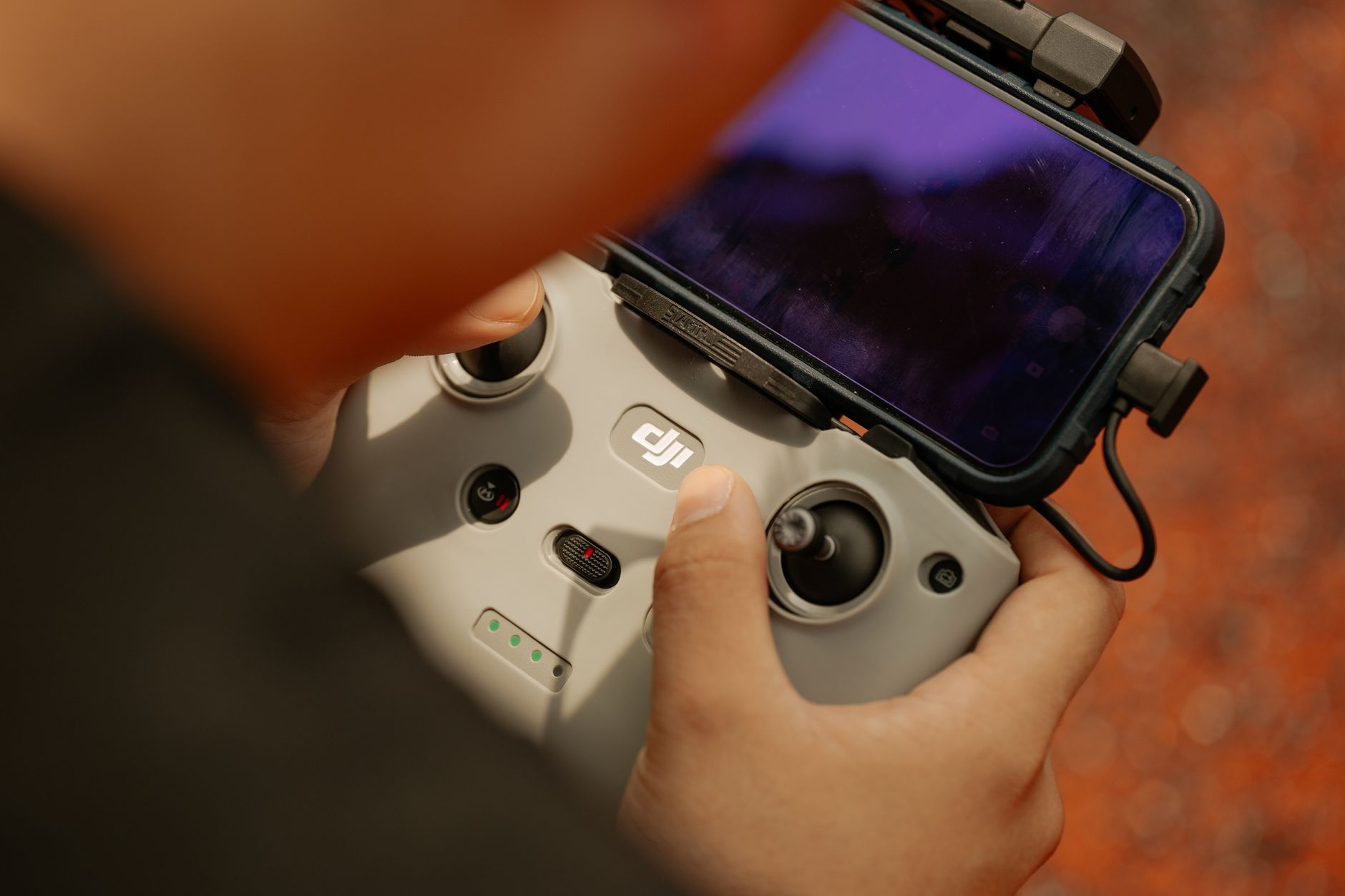 Hands using a modern drone controller with attached smartphone for scenic aerial views. — Verify document origin with documen
